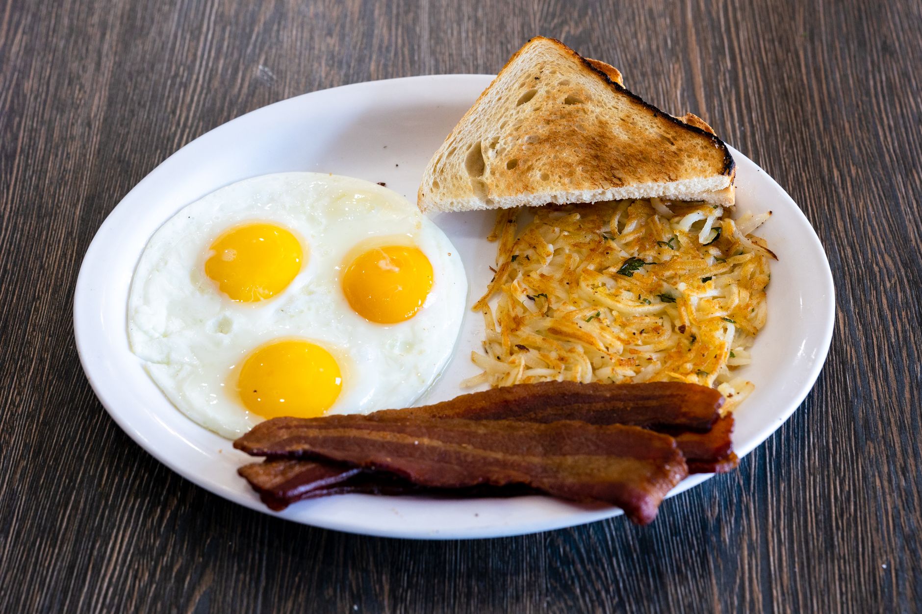Klasyczne amerykańskie śniadanie: jajka sadzone, bekon, tost i hash browns