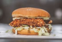 Nashville hot chicken – jak powstał pikantny kurczak z Tennessee? Chrupiąca kanapka z kurczakiem, sałatą i sosem w bułce