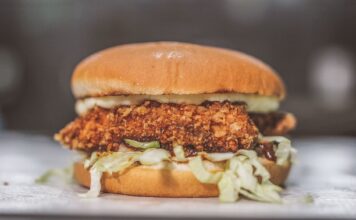 Nashville hot chicken – jak powstał pikantny kurczak z Tennessee? Chrupiąca kanapka z kurczakiem, sałatą i sosem w bułce