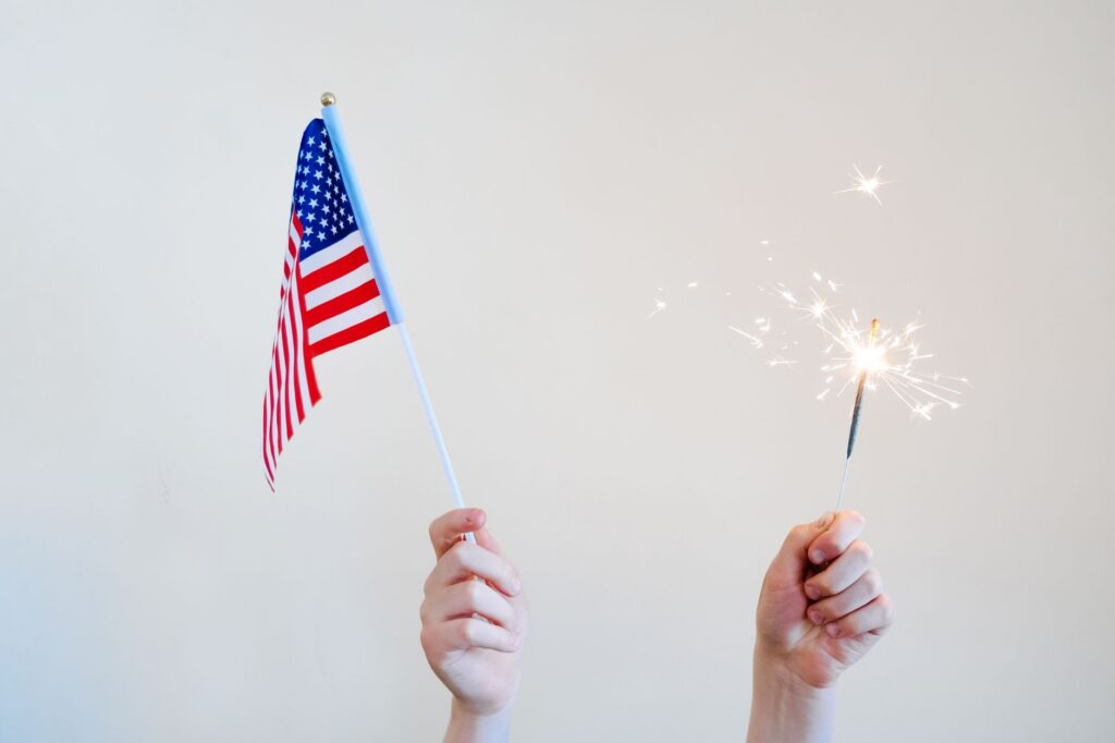 Dłonie trzymające flagę USA i zimny ogień na białym tle